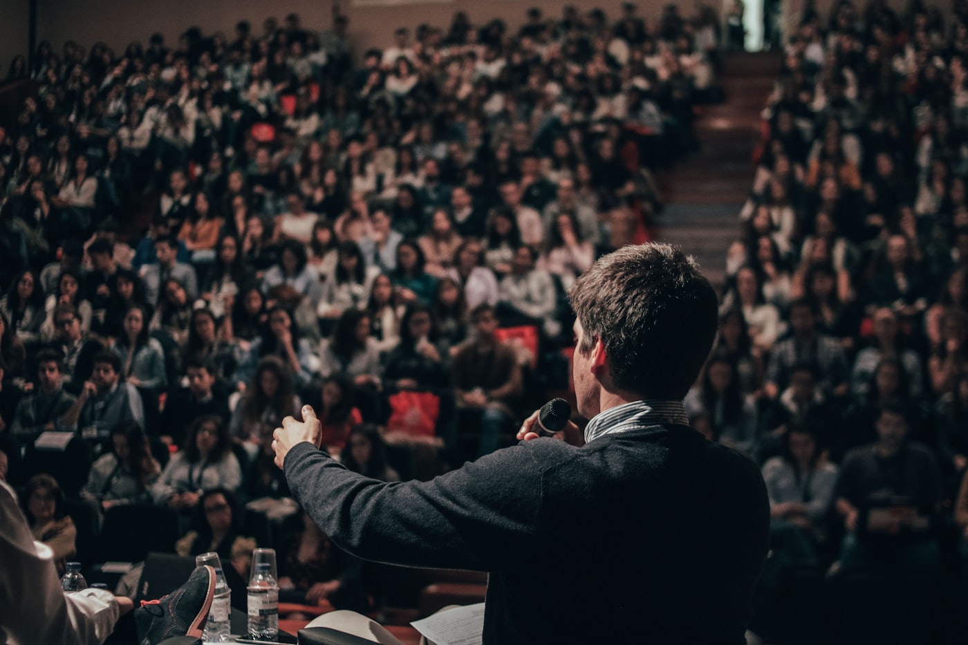 A speaker mid-gesture in front of an audience